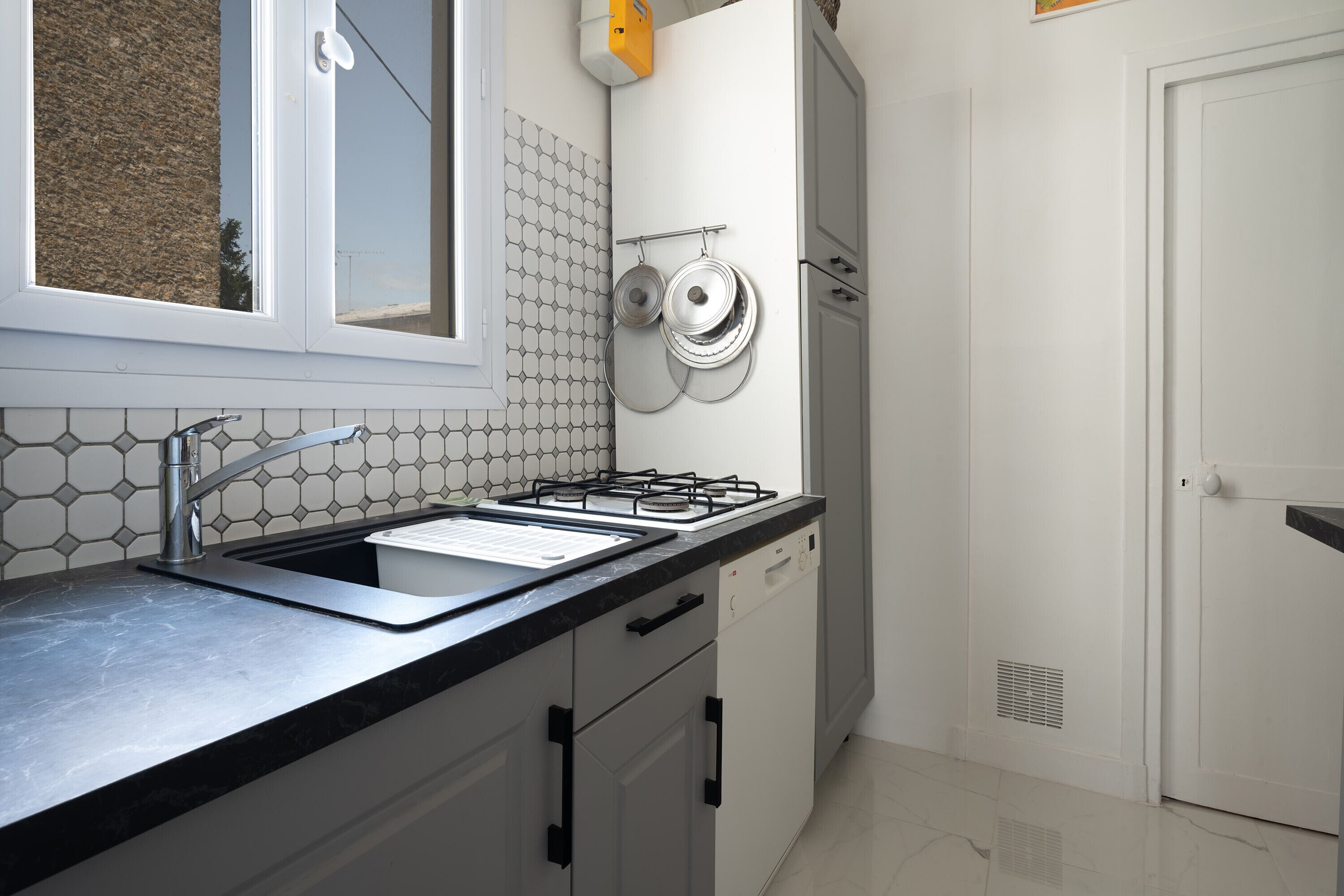 A kitchen with a gas stove, sink, and white cabinets.
