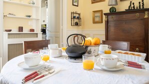 A breakfast table set with cups, a kettle, and orange juice.