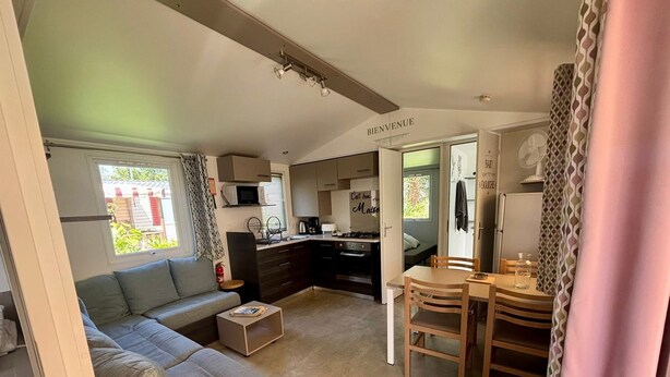 Ett kompakt bostadsutrymme med ett litet kök, en matplats och en soffa.