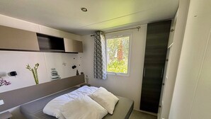 Ett litet sovrum med en säng, ett sängbord och ett fönster med gardiner.