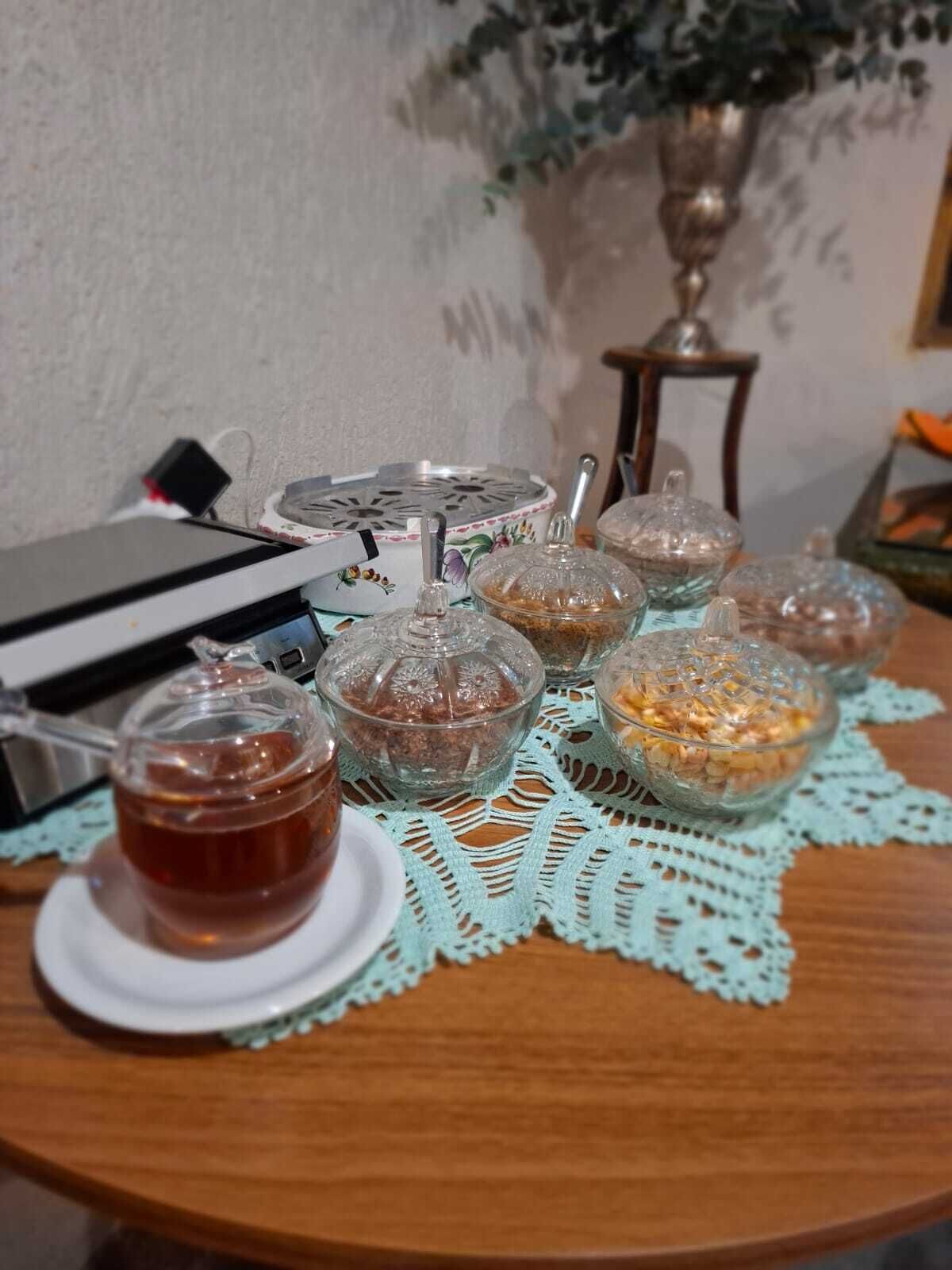 Una mesa con un juego de té, varios recipientes de vidrio con comida y un mantel decorativo.
