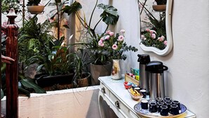 A cozy corner with a white dresser, a mirror, and a variety of potted plants.