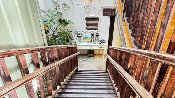 A wooden staircase with a white wall and a small desk with plants and a coffee maker.