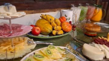 A buffet table with various food items including fruits, cheeses, and meats.