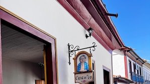 A narrow street with a building featuring a sign reading "Casa de Vó".