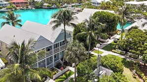 Un quartier résidentiel en bord de mer, avec des maisons, une piscine et des palmiers.
