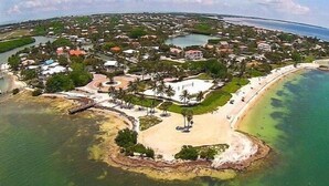 Vue aérienne d’une station balnéaire avec une plage, des étendues d’eau et des zones résidentielles.