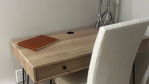 A wooden desk with a leather chair, a brown notebook, and two metallic vases.