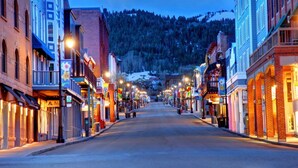 A street lined with buildings, a clear sky, and a mountain in the background.