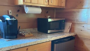Une cuisine compacte dotée de meubles en bois, d’une machine à café, d’un four à micro-ondes et d’un lave-vaisselle.