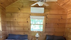 Une cabine équipée de deux lits, d’un ventilateur de plafond, d’un climatiseur et d’une fenêtre avec des stores.