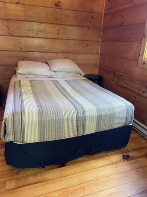 A wooden-paneled room with a bed, pillows, and a nightstand. - Cabin #3 The Sky Retreat - Off the Blue Ridge Parkway (Purlear)