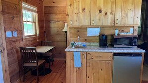 A compact kitchen with wooden cabinets, a built-in microwave, a coffee maker, and a dishwasher. - Cabin #3 The Sky Retreat - Off the Blue Ridge Parkway (Purlear)