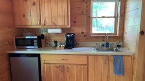 Eine kleine Küche mit Holzschränken, einer Mikrowelle, einer Kaffeemaschine und einem Geschirrspüler.