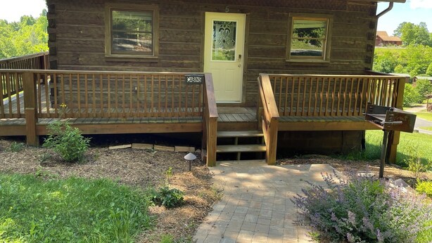 Eine rustikale Holzhütte mit einer Holzterrasse, einer Haustür und einer kleinen Veranda.