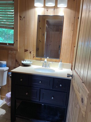 A wooden bathroom with a sink, mirror, and dark cabinets. - Cabin #6 The Sky Retreat - Off the Blue Ridge Parkway (Purlear)