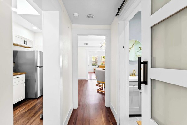 A hallway with a kitchen on the left, a dining area in the center, and a bathroom on the right.
