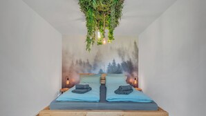 A bedroom with a bed, two bedside tables, a hanging plant, and a forest mural on the wall. - Novita Apartment - balcony | free parking | central (Bad Harzburg)