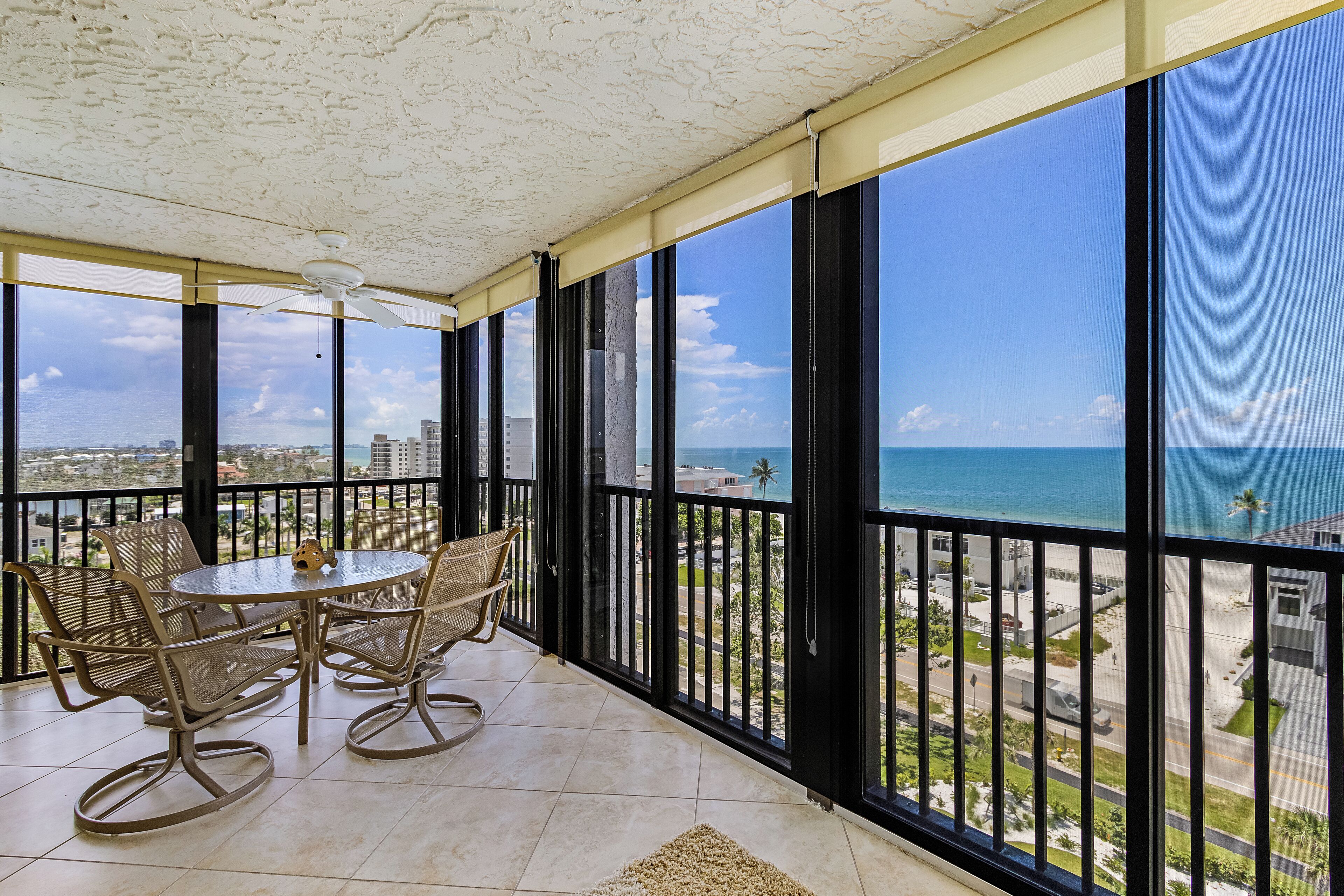 Uma varanda com vista para o oceano, mobiliada com uma mesa e cadeiras.