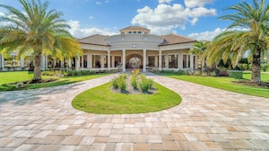 A large, two-story building with a central courtyard, surrounded by palm trees and a well-maintained lawn. - Enjoy views of the immaculate green from your screened lanai at Lakeside National - Golfside Escape (Bradenton)