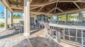 An outdoor patio area with multiple seating arrangements, a bar, and ceiling fans. - Enjoy views of the immaculate green from your screened lanai at Lakeside National - Golfside Escape (Bradenton)
