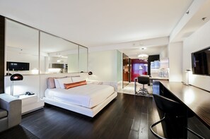 Une chambre d’hôtel moderne équipée d’un grand lit, d’un bureau, d’une chaise, d’une télévision et d’un miroir.