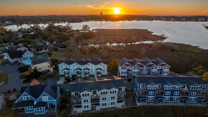 Et kystnært boligområde med flere toetagers huse, en lysthavn og en solnedgang over vandet.
