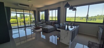 Uma sala ampla com uma janela grande, um sofá, uma mesa de centro e uma ilha de cozinha.