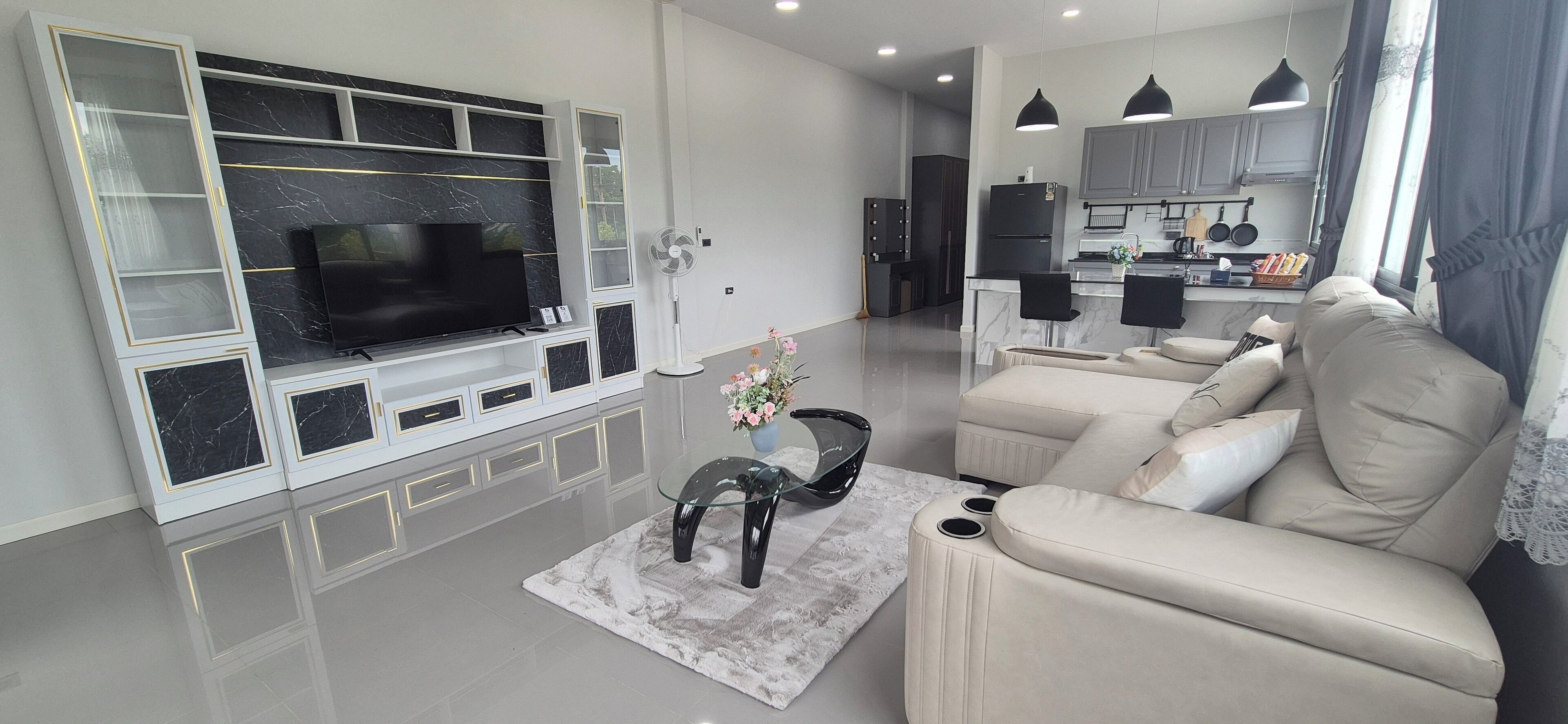 Una sala de estar moderna con un televisor de pantalla plana, una mesa de centro de vidrio y un sofá color beige.