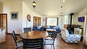 Un salon chaleureux avec une table ronde en bois, un canapé bleu et une cheminée.