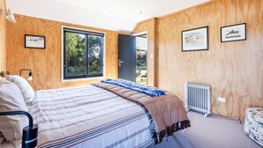 Une chambre à coucher avec un lit, des murs en bois, une fenêtre et un radiateur.