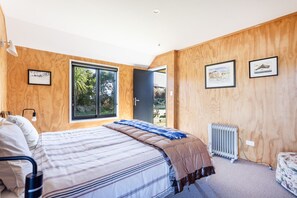 Quarto com cama, paredes de madeira, janela e radiador.