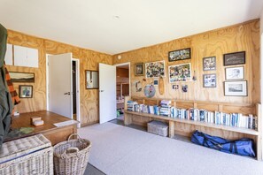 Una habitación con paredes de madera, una estantería llena de libros, un espejo y varios cuadros enmarcados.