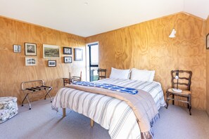 Une chambre à coucher avec un lit, des murs en bois, une fenêtre et plusieurs tableaux encadrés.
