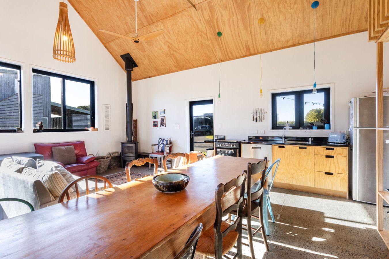 A modern kitchen with wooden cabinets, a dining table, and a built-in stove.