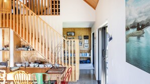 Un escalier en bois mène à une chambre située en mezzanine, qui offre une vue sur un paysage enneigé.