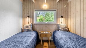 Una habitación pequeña y acogedora con dos camas, un escritorio de madera y una ventana con vistas a zonas verdes.