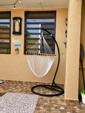 A hammock chair on a tiled patio with a textured wall and a window with blinds. - Hidden Gem—Two Houses—Private Pool—Near the Beach (Puerto Morelos)
