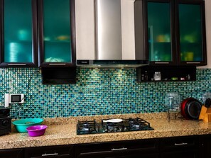 A kitchen with a tiled backsplash, a gas stove, and various kitchen items.