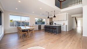 Una cocina espaciosa con una isla grande, piso de madera y abundante luz natural proveniente de amplios ventanales.