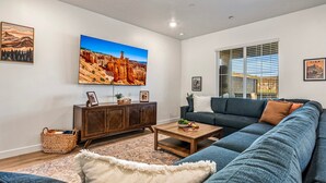 A living room with a sectional sofa, a coffee table, a cabinet, and a large TV mounted on the wall. - Skyline 1694, Hot Tub, Arcade Games, Nintendo Switch, Community Amenities! (Washington)