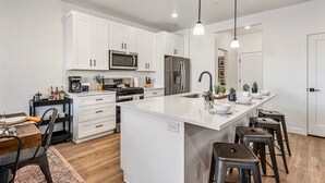 A modern kitchen with white cabinetry, a central island, stainless steel appliances, and a bar stool seating area. - Skyline 1694, Hot Tub, Arcade Games, Nintendo Switch, Community Amenities! (Washington)