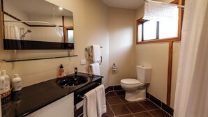 Een moderne badkamer met een zwarte wastafel, wit toilet en een grote spiegel.