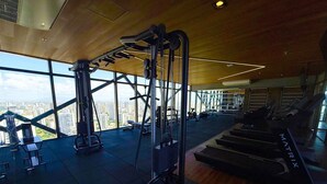 A gym with exercise equipment, large windows, and a view of the city. - Beach Class Meireles (Fortaleza)