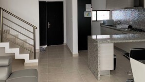 Una cocina moderna con encimera de granito, electrodomésticos de acero inoxidable y salpicadero negro.