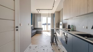 A modern kitchen with a built-in stove, bar stools, and a view of the city through large windows.