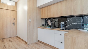 Et moderne køkken med træskabe, en backsplash i sort marmor og en stålvask.