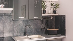 A modern kitchen with a built-in sink, stainless steel cabinets, and a black pot on the countertop.