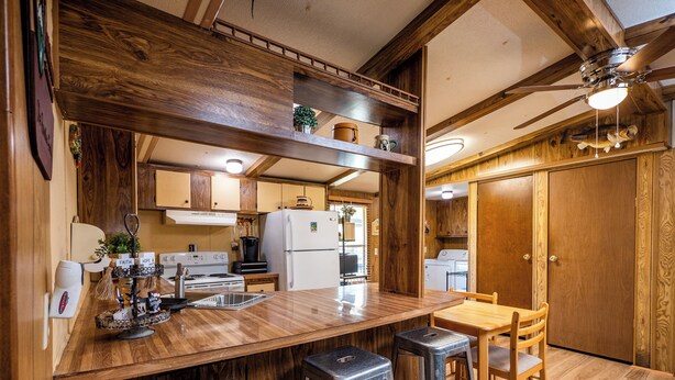 A kitchen with wooden cabinets, a countertop, a sink, a stove, and a ceiling fan. - Charming Canal Waterfront 3/2 in Salt Springs (Salt Springs)