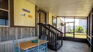 A covered outdoor area with a wooden table and blue chairs, a staircase, and a view of a residential area. - Charming Canal Waterfront 3/2 in Salt Springs (Salt Springs)